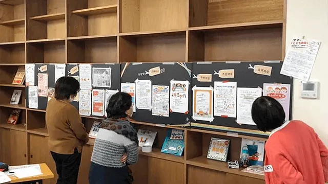 写真：掲示板に貼られたチラシを読む方達